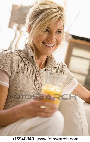 Stock Image - Woman drinking a glass of orange juice. Fotosearch