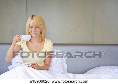 Stock Photograph - Woman drinking coffee in bed. Fotosearch
