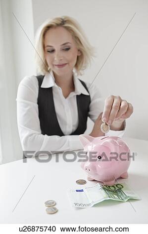 Woman dropping money into piggy bank View Large Photo Image Stock Image - Woman dropping money into piggy bank. Fotosearch
