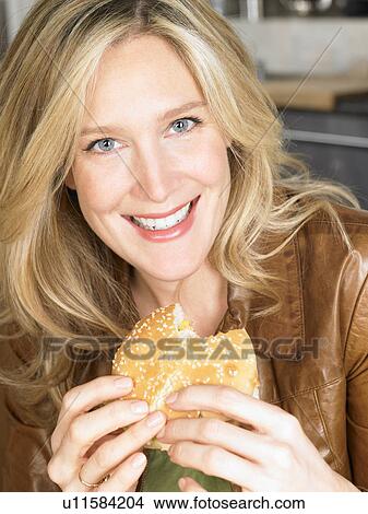 Woman eating a burger View Large Photo Image Picture - Woman eating a burger. Fotosearch