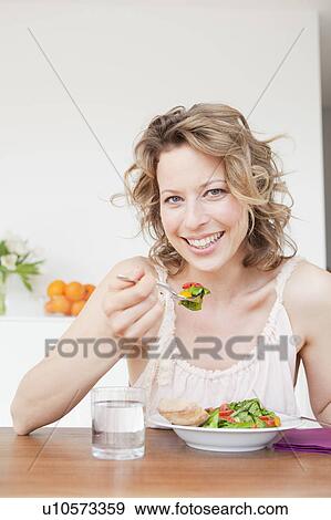 Woman eating mixed salad on table View Large Photo Image Stock Photo - Woman eating mixed salad on table. Fotosearch