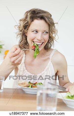 Woman eating mixed salad on table View Large Photo Image Stock Photo - Woman eating mixed salad on table. Fotosearch