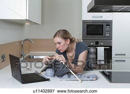 Stock Photo - Woman following knitting pattern on line. Fotosearch