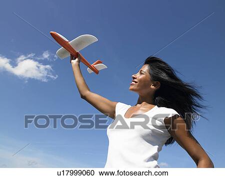 Woman holding a plane towards the sky View Large Photo Image Stock Image - Woman holding a plane towards the sky. Fotosearch