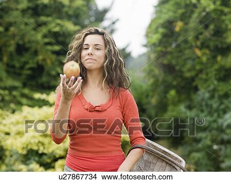 Picture - Woman holding basket with apple in hand. Fotosearch