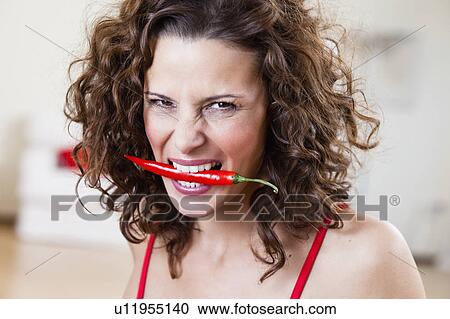Stock Image - Woman Holding Chili With Teeth. Fotosearch