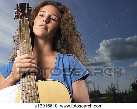 Woman holding her guitar View Large Photo Image Stock Photo - Woman holding her guitar. Fotosearch