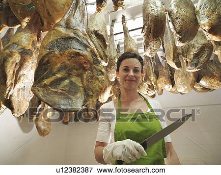 Woman holding knife with hams hanging View Large Photo Image Stock Photo - Woman holding knife with hams hanging. Fotosearch