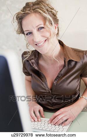 Stock Photo - Woman in front of a computer smiling. Fotosearch