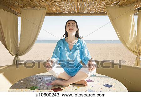Stock Image - Woman in yoga pose on beach. Fotosearch