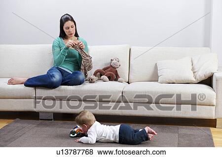 Woman knitting, baby playing on floor View Large Photo Image Stock Photo - Woman knitting, baby playing on floor. Fotosearch