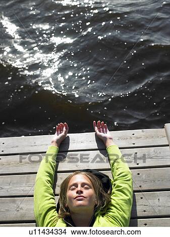 Picture - Woman laying down on a deck. Fotosearch