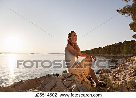 Woman listening to shell at beach View Large Photo Image Stock Image - Woman listening to shell at beach. Fotosearch