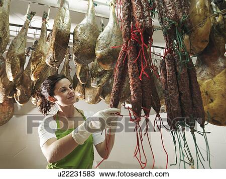 Stock Image - Woman looking at hanging chorizos. Fotosearch
