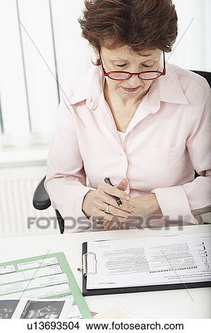 Woman looking at paperwork View Large Photo Image Picture - Woman looking at paperwork. Fotosearch