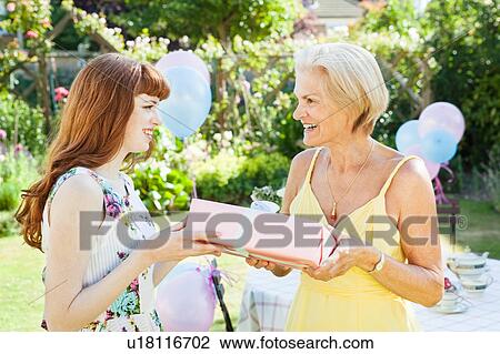 Stock Image - woman offers present to mature woman.. Fotosearch