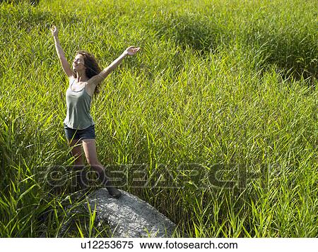 Stock Photography - Woman on a rock, surrounded by nature. Fotosearch