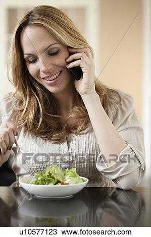 Woman on cellphone eating salad View Large Photo Image Stock Image - Woman on cellphone eating salad. Fotosearch