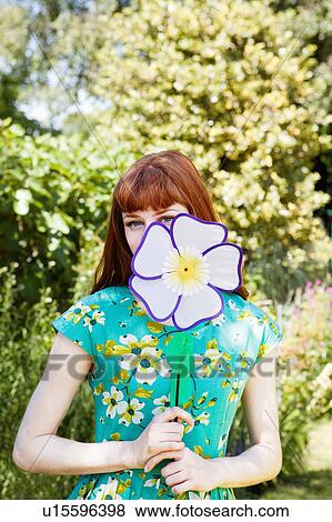 Stock Photo - woman peeping from behind fabric flower.. Fotosearch