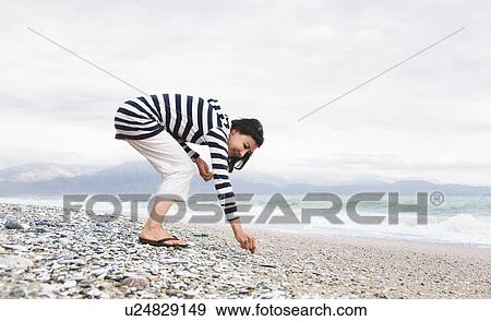 Woman picking shells on a beach View Large Photo Image Stock Photo - Woman picking shells on a beach. Fotosearch