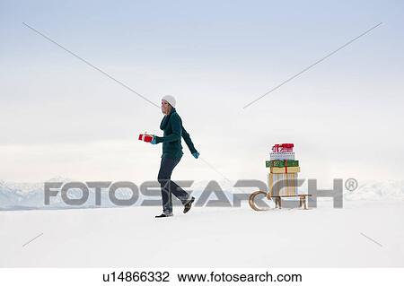 Woman pulls Christmas presents on sled View Large Photo Image Stock Image - Woman pulls Christmas presents on sled. Fotosearch
