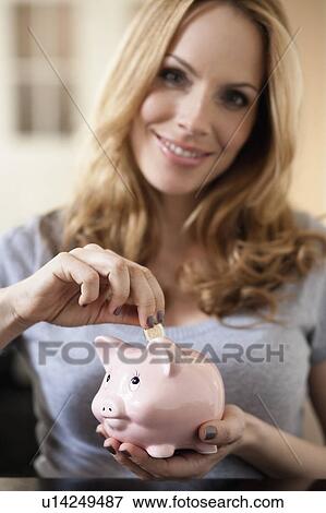 Woman putting coin in to piggy bank View Large Photo Image Stock Photo - Woman putting coin in to piggy bank. Fotosearch