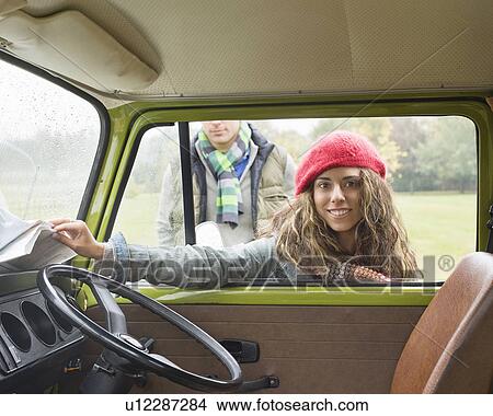 Picture - Woman reaching for map in camper van. Fotosearch