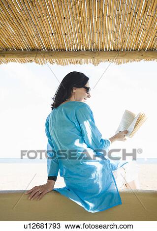 Stock Image - Woman Reading book on beach. Fotosearch