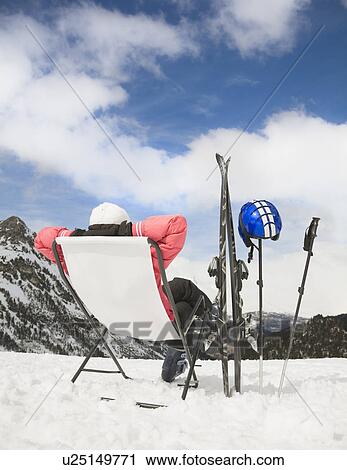 Stock Image - Woman relaxing in snowy mountain scene. Fotosearch