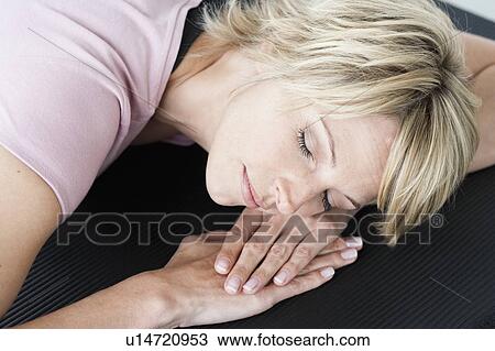 Woman relaxing on yoga mat View Large Photo Image Stock Image - Woman relaxing on yoga mat. Fotosearch
