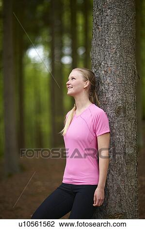 Stock Image - Woman running, leaning against tree. Fotosearch