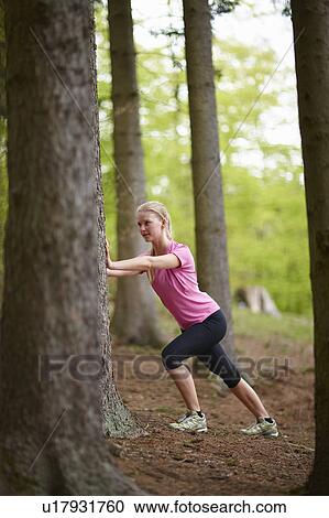 Woman running, stretching against tree View Large Photo Image Stock Image - Woman running, stretching against tree. Fotosearch