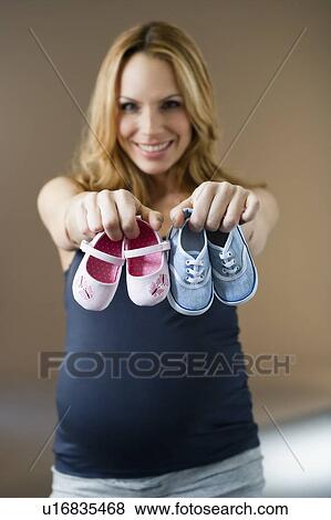 Stock Photo - Woman showing baby shoes. Fotosearch