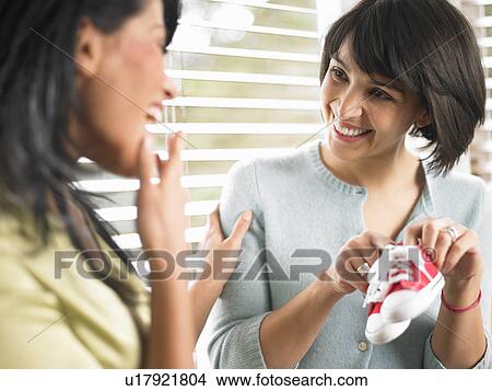 Woman showing baby shoes to her friend View Large Photo Image Picture - Woman showing baby shoes to her friend. Fotosearch
