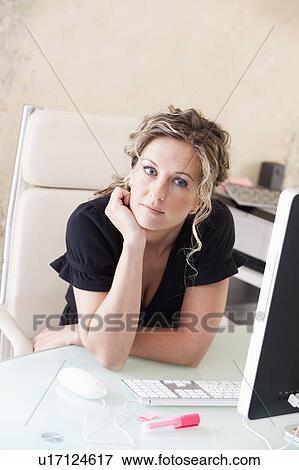 Woman sitting at her desk daydreaming View Large Photo Image Stock Photo - Woman sitting at her desk daydreaming. Fotosearch
