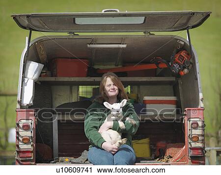 Woman sitting in van boot holding lamb View Large Photo Image Stock Image - Woman sitting in van boot holding lamb. Fotosearch