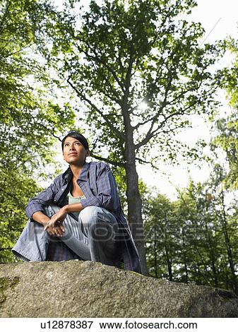 Woman sitting on a rock, in the woods View Large Photo Image Stock Photo - Woman sitting on a rock, in the woods. Fotosearch