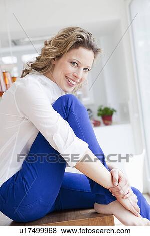 Woman sitting on table smiling View Large Photo Image Stock Photo - Woman sitting on table smiling. Fotosearch