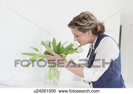 Stock Image - Woman smelling on white tulips. Fotosearch