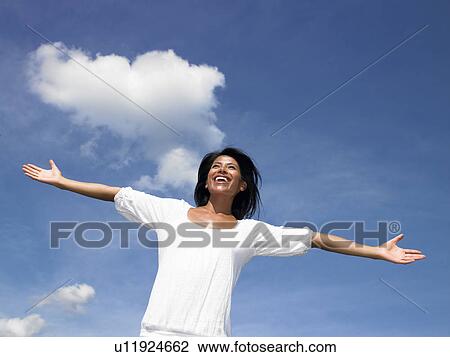 Stock Image - Woman spreading her arms towards the sky. Fotosearch