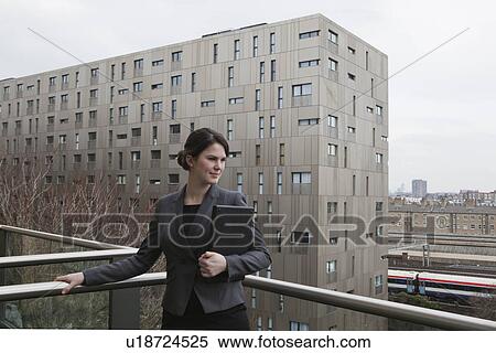Woman standing with laptop on balcony View Large Photo Image Stock Photography - Woman standing with laptop on balcony. Fotosearch
