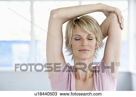 Stock Image - Woman stretching arms with eyes closed. Fotosearch