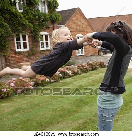Stock Photography - Woman swinging child outdoors. Fotosearch