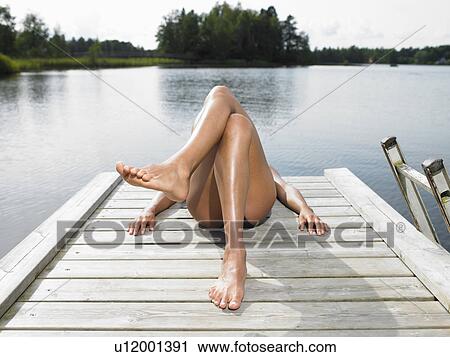 Stock Image - Woman tanning on a dock. Fotosearch
