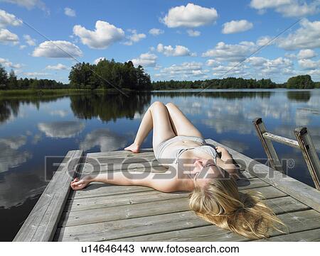 Stock Image - Woman tanning on a dock. Fotosearch