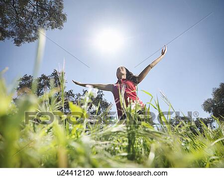 Stock Image - Woman with arms raised to the sky. Fotosearch