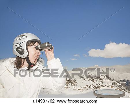 Stock Image - Woman with binoculars in snowy mountains. Fotosearch