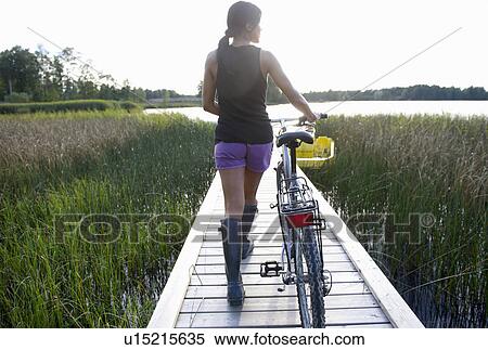 Stock Photography - Woman with her bike, on a dock. Fotosearch