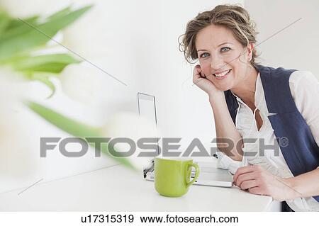 Woman with laptop and a cup of coffee View Large Photo Image Stock Photo - Woman with laptop and a cup of coffee. Fotosearch