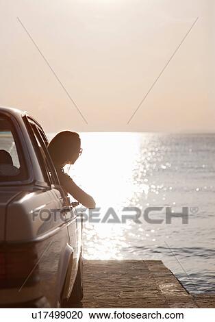 Stock Image - Woman with oldtimer by sea. Fotosearch